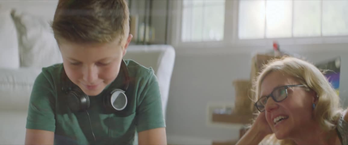 Boy does homework sitting on the floor of the living room with his mother