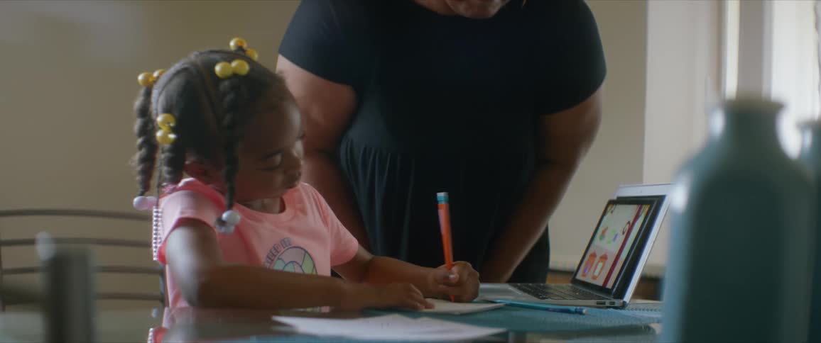 A woman checks on a girl doing homework