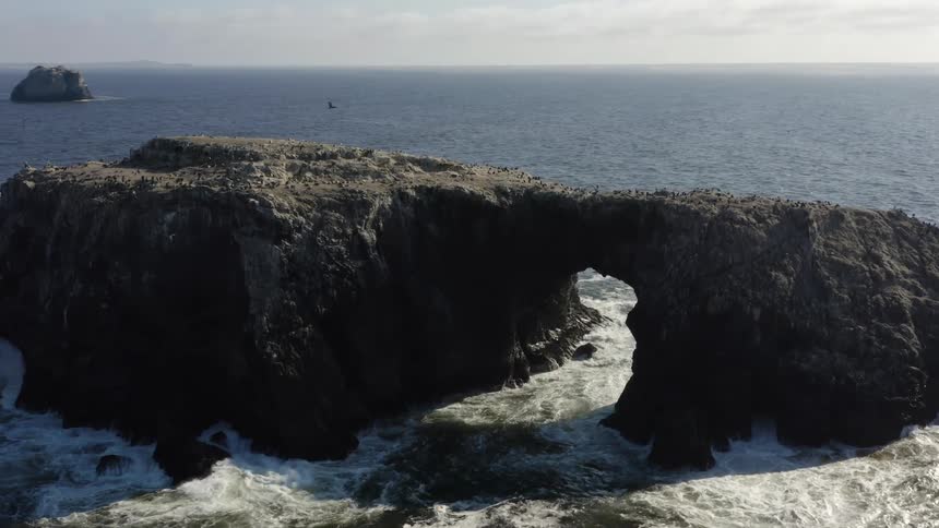 Arch rock formation off the coastline on a cloudy day