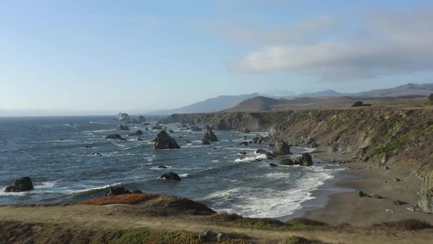 Waves roll into rocky coastline bluff on a cloudy day