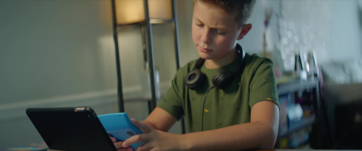 Young boy doing homework using a tablet and a calculator at home