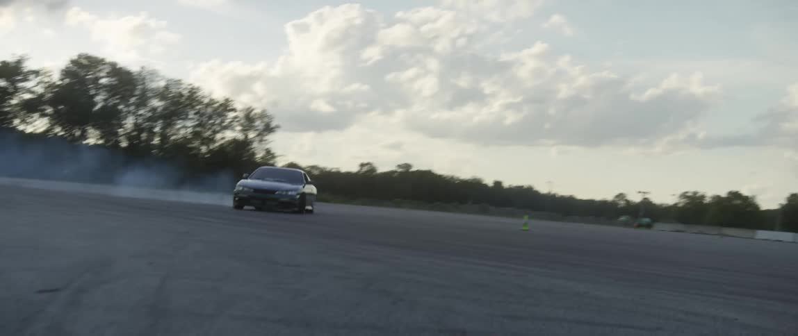A person driving a race car skids across the pavement