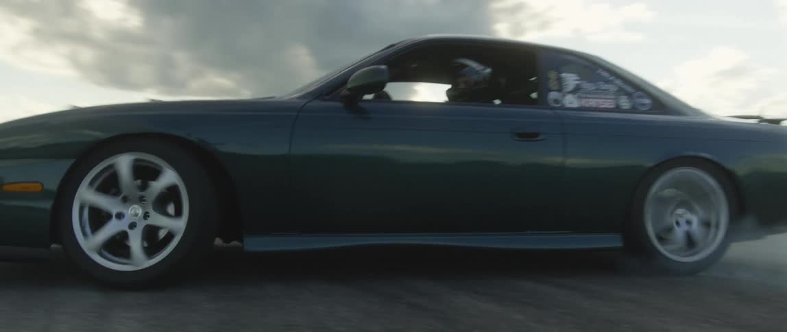 A man wears a helmet while racing a car around a track at a stadium