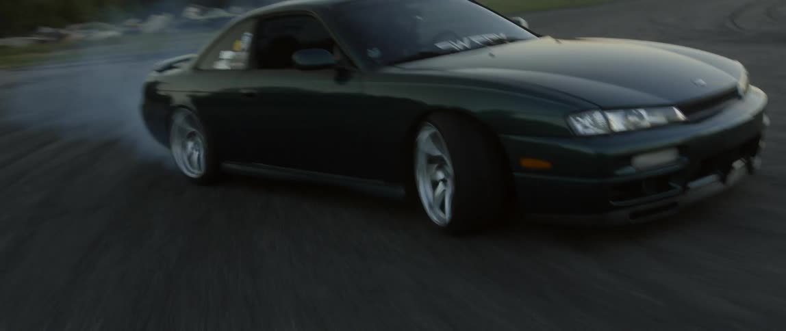 A sports car races quickly around an outdoor race track