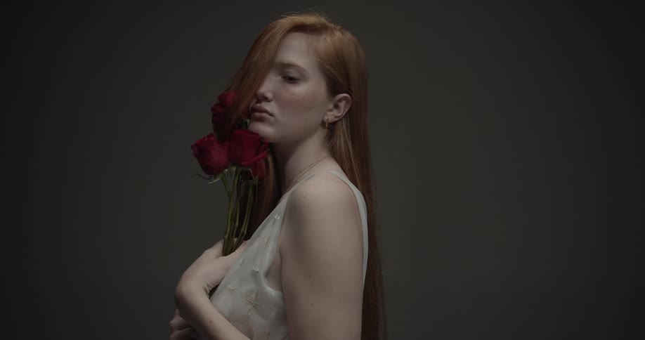 A teenage girl runs roses over her face
