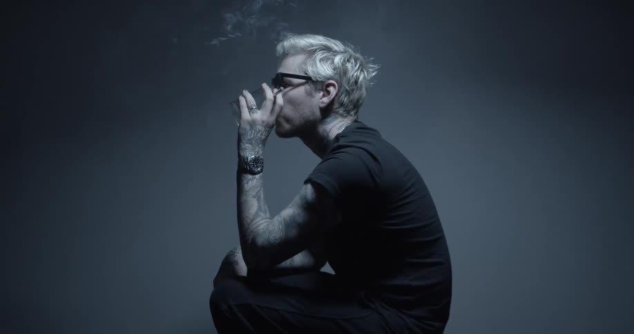 Man holding a cigarette drinking alcohol from a short glass