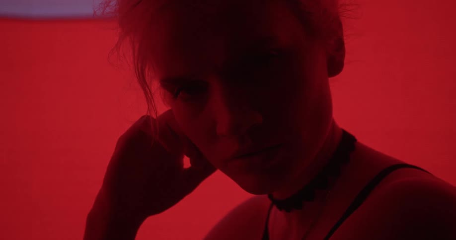 Young blonde woman looking at the camera in front of a colorful digital display
