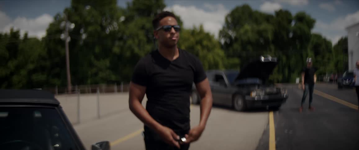 A man gets out of his park thats parked behind a stadium and greets a friend