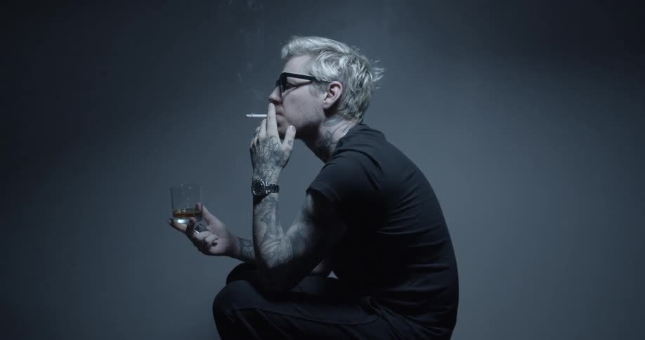 A man is sitting in a room and smoking a cigarette