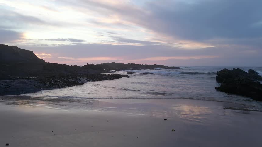 The sun is setting above the ocean water at the beach