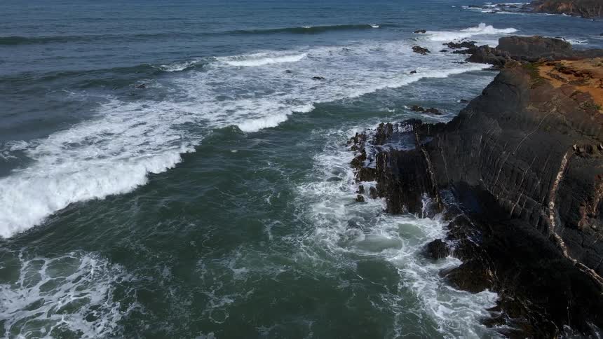 Waves roll in over rocks at coastline bluff