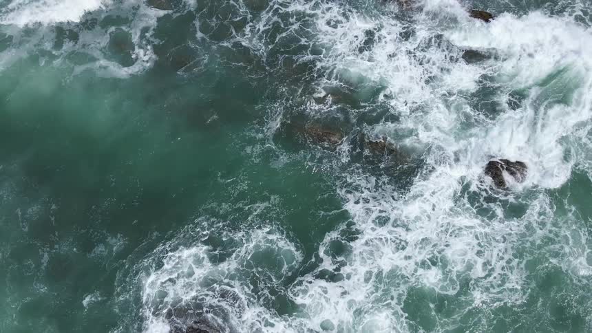 Aerial view of ocean waves crashing against the rocky shores