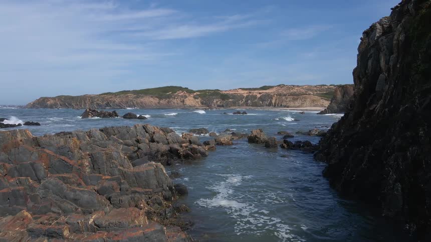Landscape with ocean and rocks and land with blue skies