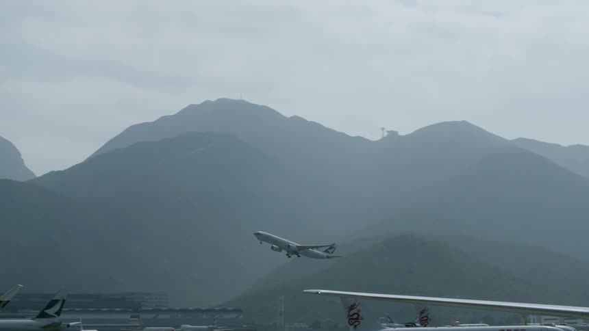 Large plane taking off from an airport with mountains in the background