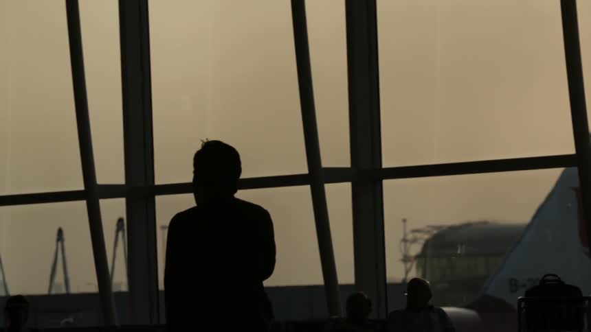 A man is walking by a window in a dark airport