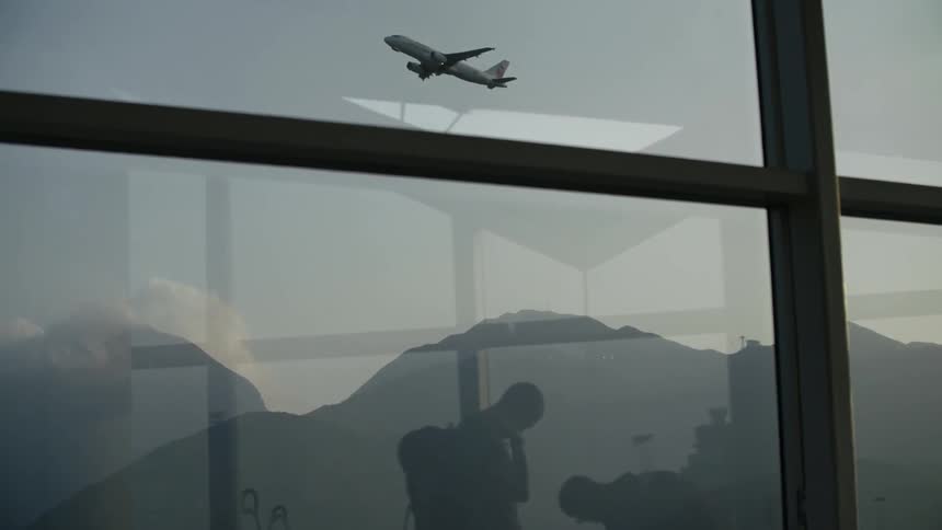 Airplanes take off and taxi outside an airport terminal window