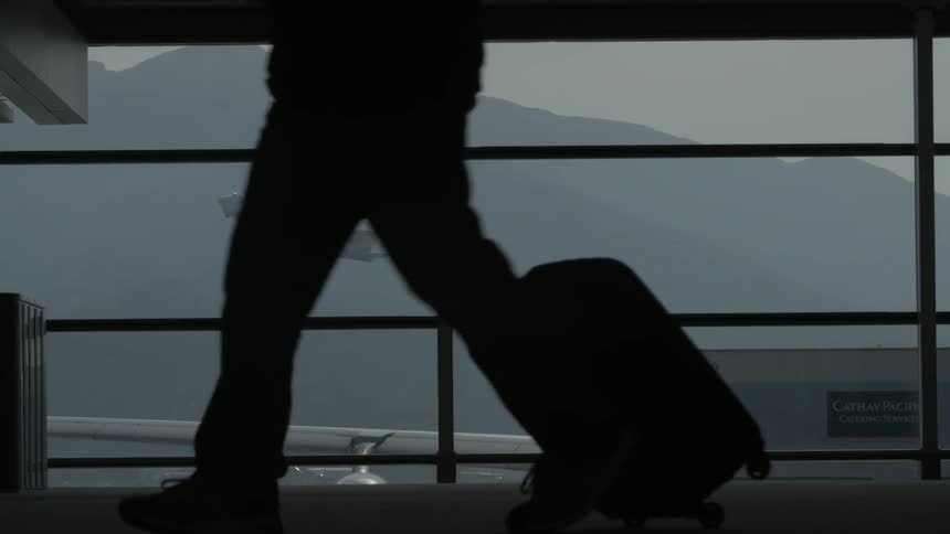 A plane takes off outside as people walk in a building