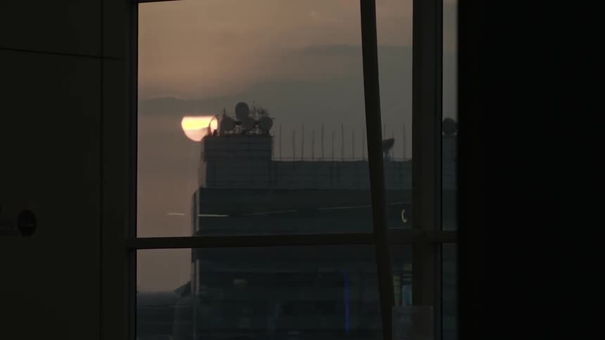 The sun rises behind a building with satellites on it