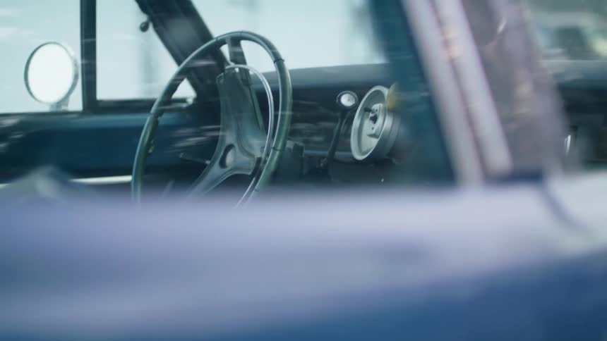 A vehicle with a steering wheel and a rearview mirror with a building in the background