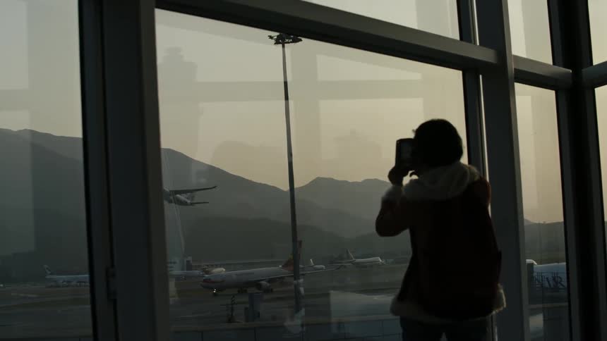 A person films an airliner taking off from an airport