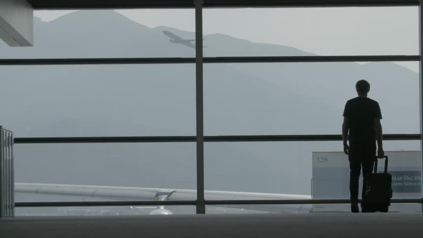 A person stands near a window in an airport