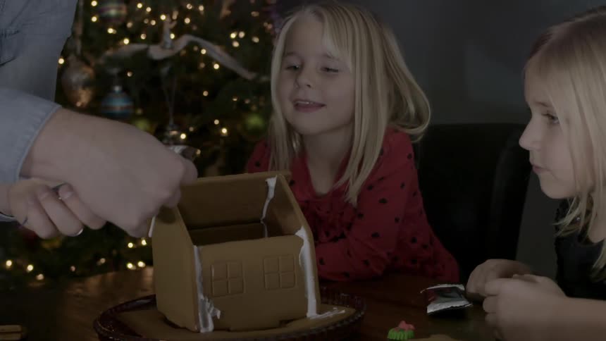 Children watch as a gingerbread house is built
