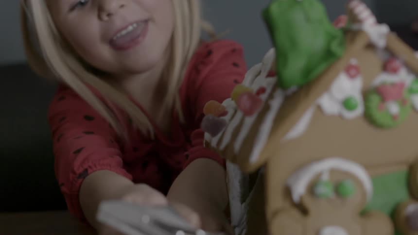 A girl decorates a gingerbread house
