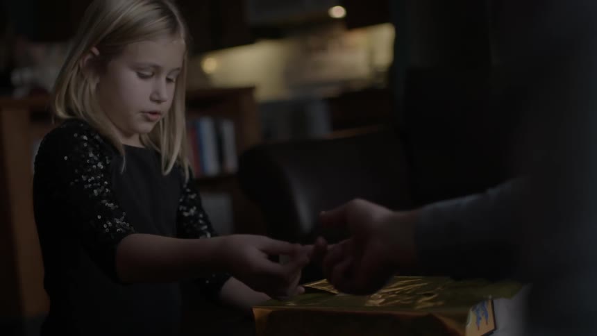 Person handing an object to a little girl
