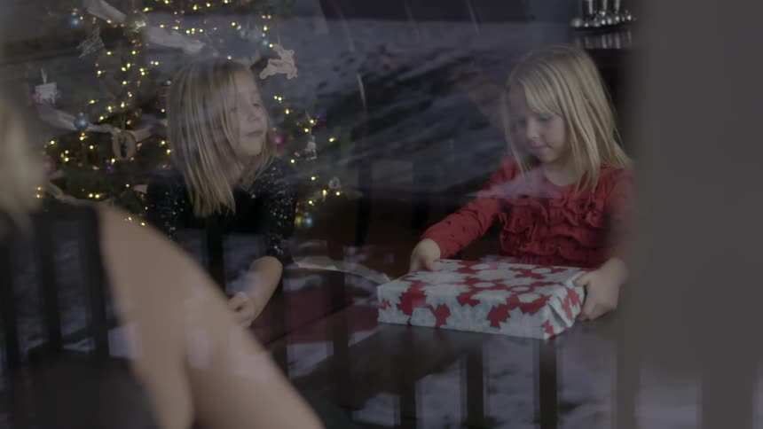 A little girl setting a christmas present on a table