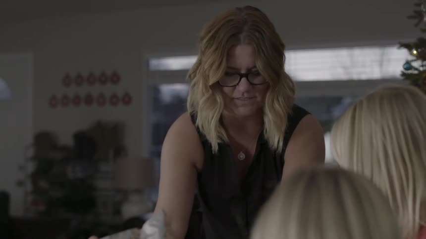 Spectacled blonde woman showing something to two small blonde girls