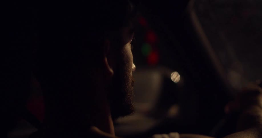 A man drives a car on a street at night