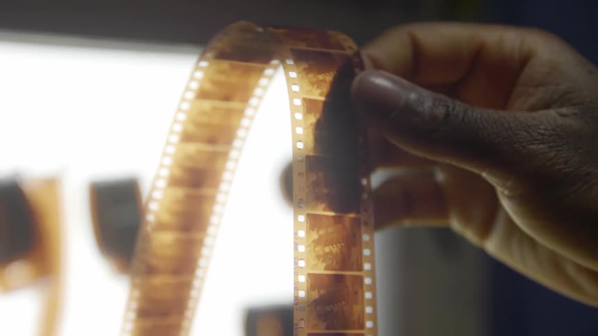 A person holding and examining a film strip