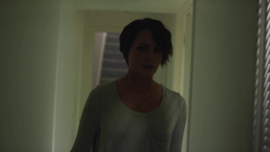 A woman walking down a hallway with doors with stairs in the background