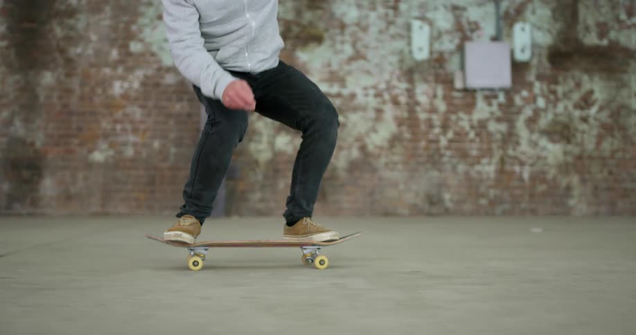 A skateboarder in jeans and a sweatshirt does a kickflip on a skateboard