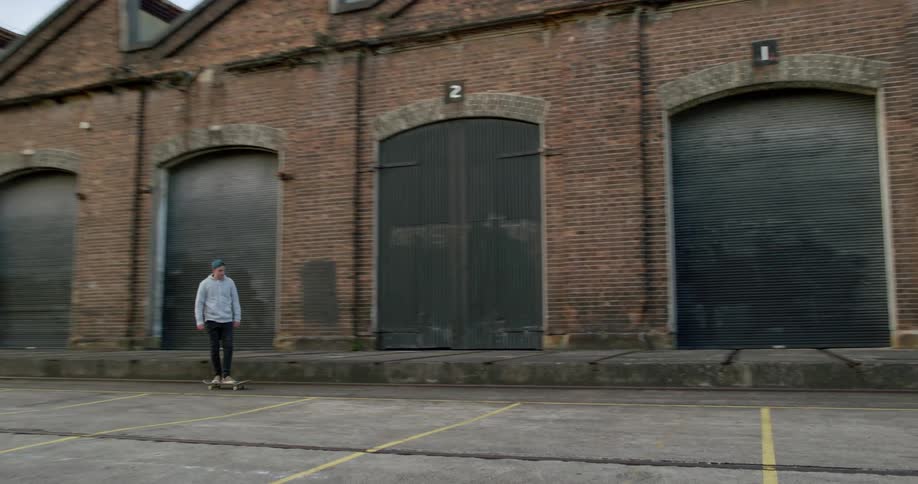 Man skateboarding down pavement in front of garages
