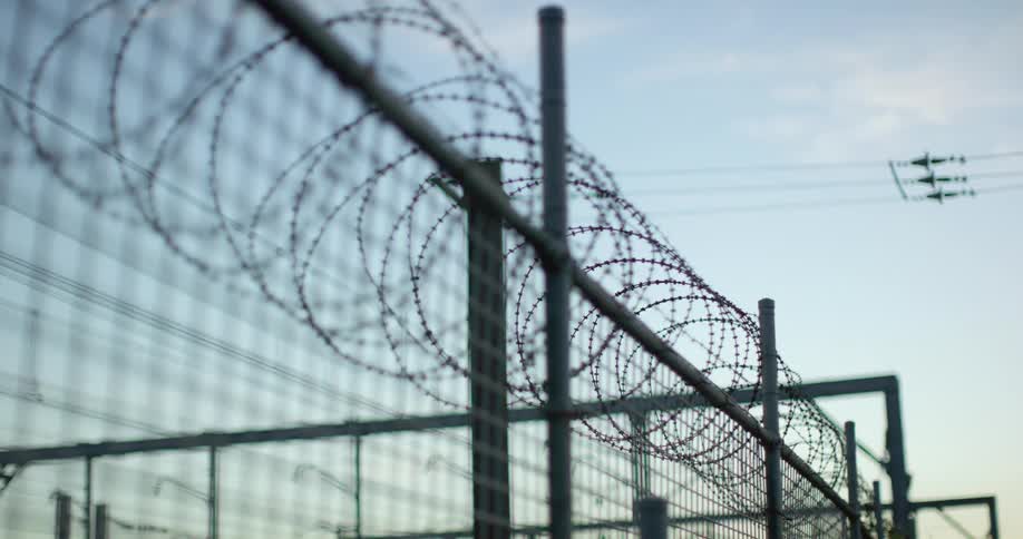 Barbed wire is looped along the top of a metal fence at a power station