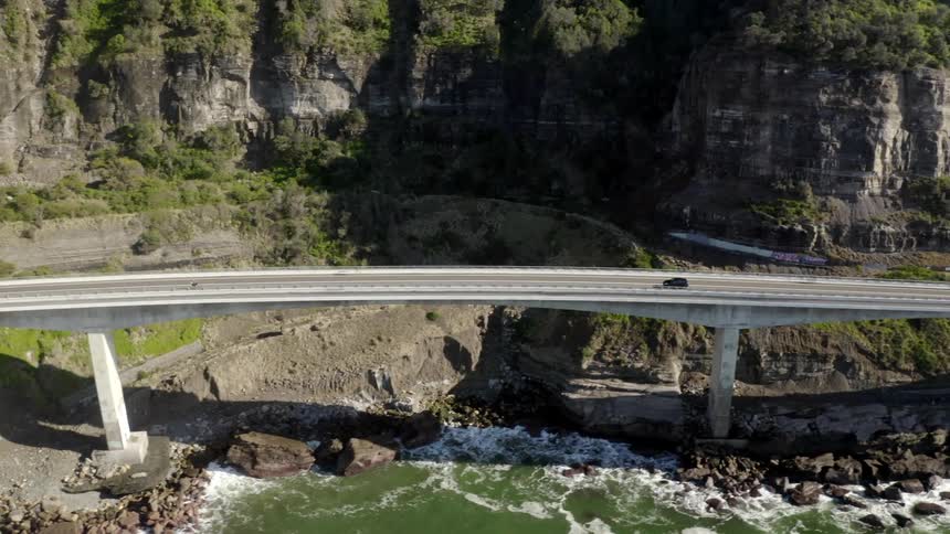 A car driving along a highway bridge near the coast