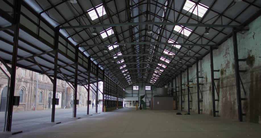 Inside of an old building with one wall of doors open to show old buildings across the street outside