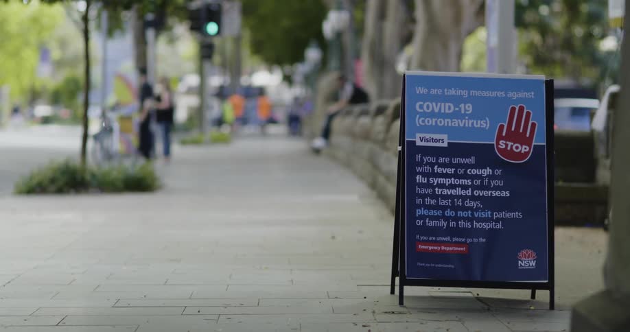 A sign on a sidewalk in a small town alerting people to covid19