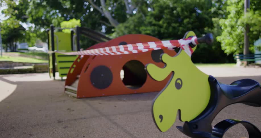 A playground is blocked off with red and white checkered tape connected to a slide and a ride