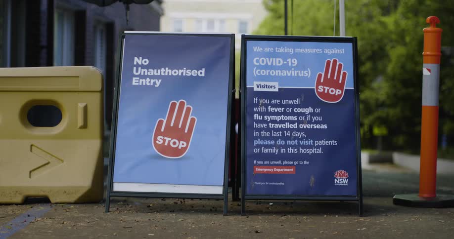 Two covid19 signs with warning labels next to a barrier outdoors during the daytime