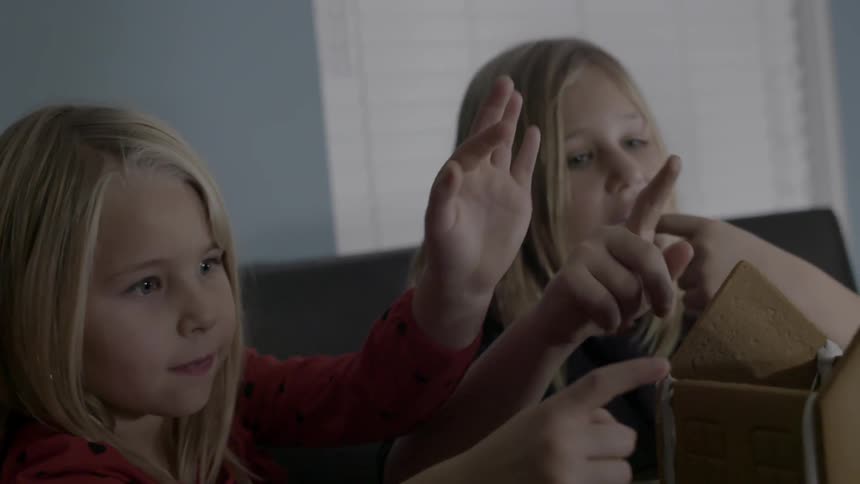 Two little girls making a gingerbread house