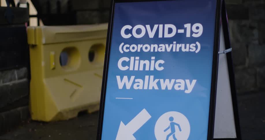 Sign to a covid 19 clinic on an easel in the sidewalk of a street