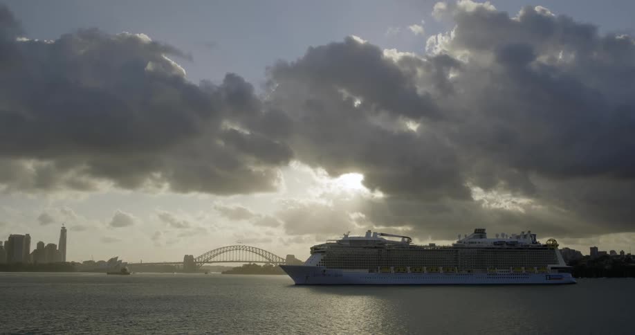 A multi deck cruise ship is docked near a city skyline