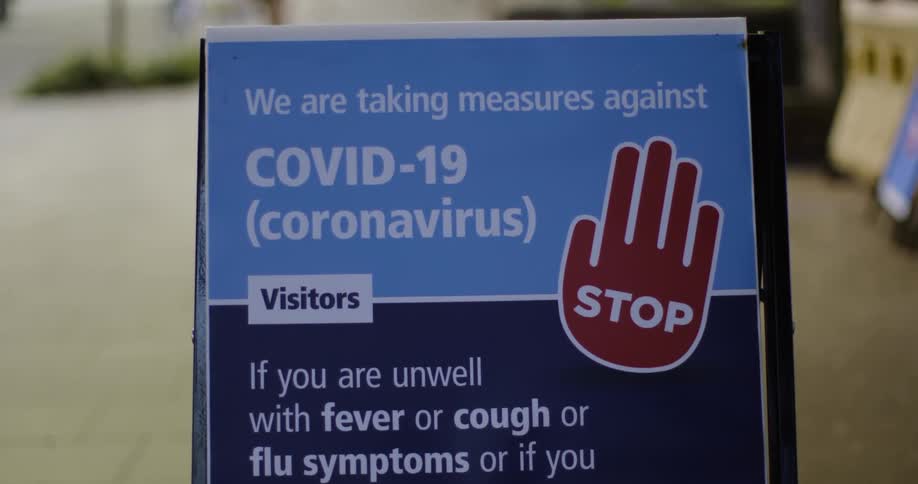 Street sign on an easel warning visitors to check for covid symptoms