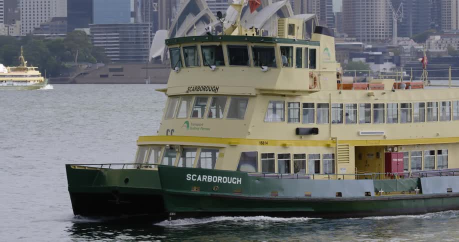 A ferry boat moves through the water near a large metropolitan city