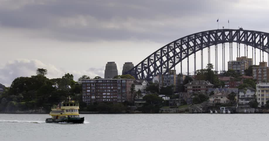 Passenger ferry driving through a river next to an arch way over a coastal city