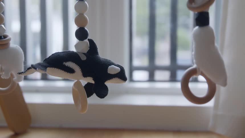 Plush stuffed felt orca mobile toy hanging over a crib