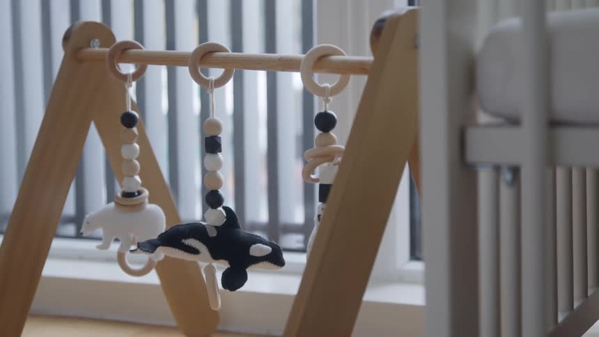 Wooden toy with small black and white stuffed animals attached to it in a baby room