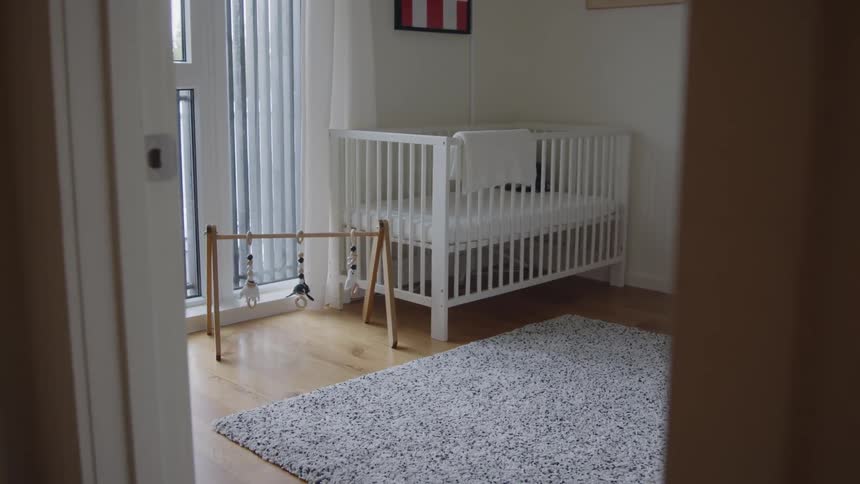 White crib and baby mobile play gym inside a modern baby room at home